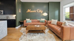Una sala de estar moderna con un sofá de cuero, una mesa de centro y una guitarra colgada en la pared.