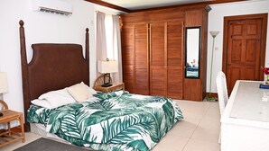 Une chambre à coucher avec un lit, une armoire en bois, une petite table et une chaise.