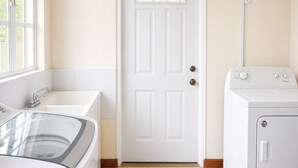 Une buanderie avec une porte blanche, un lave-linge et un évier.