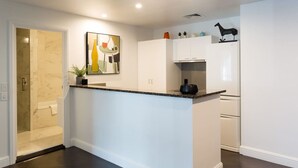 Une cuisine moderne avec des meubles blancs, un plan de travail en marbre et un saladier noir posé sur l’îlot central.