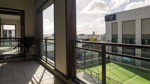 Un balcon donnant sur un court de tennis et un bâtiment sur lequel on peut voir une enseigne.