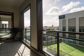 Een balkon met uitzicht op een tennisbaan en een gebouw met een bord.