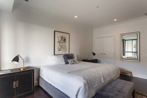Een slaapkamer met een groot bed, nachtkastjes, een kledingkast, een ingelijste foto aan de muur en een raam met uitzicht.