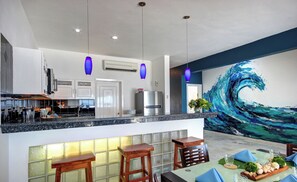 A modern kitchen with a central island, bar stools, and a dining area with a table set for two.