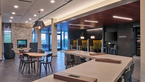 A modern indoor space with a long table, chairs, a fireplace, and a TV. - Courtyard by Marriott Petoskey at Victories Square (Petoskey)