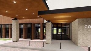 A modern building entrance with a brick pathway, wooden ceiling, and stone pillars. - Courtyard by Marriott Petoskey at Victories Square (Petoskey)