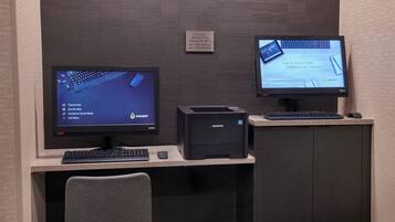 A workspace with two monitors, a keyboard, a printer, and a chair.