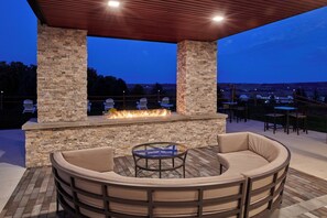 An outdoor patio with a stone fireplace, cushioned seating, and a view of the landscape. - Courtyard by Marriott Petoskey at Victories Square (Petoskey)