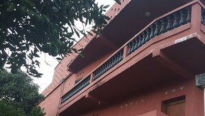 Een meerlaags gebouw met balkons, een hekpoort en omliggende beplanting.