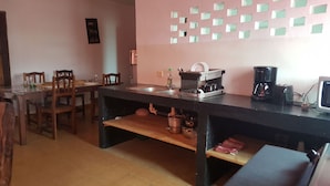 Een keuken met een zwart aanrecht, houten stoelen, een gootsteen en een koffiezetapparaat.