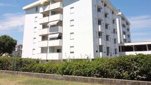 Un immeuble blanc à plusieurs étages, doté de balcons et d’un toit plat.