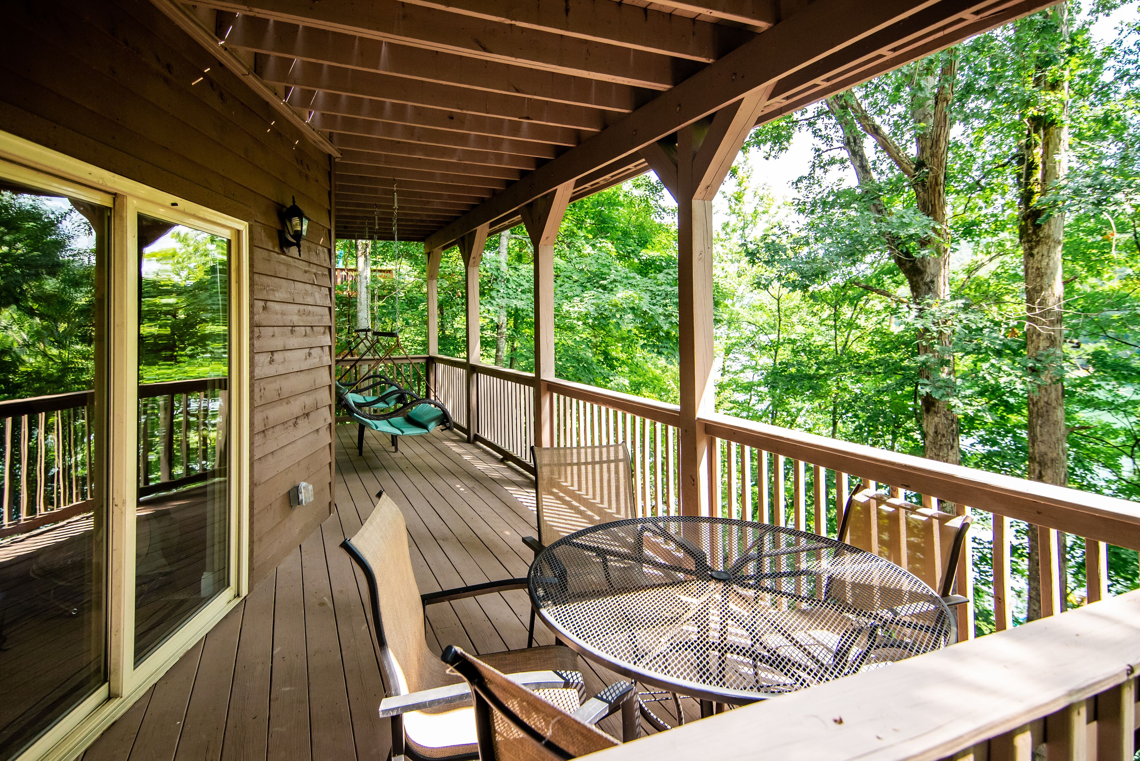 A wooden deck with a table and chairs, surrounded by trees.