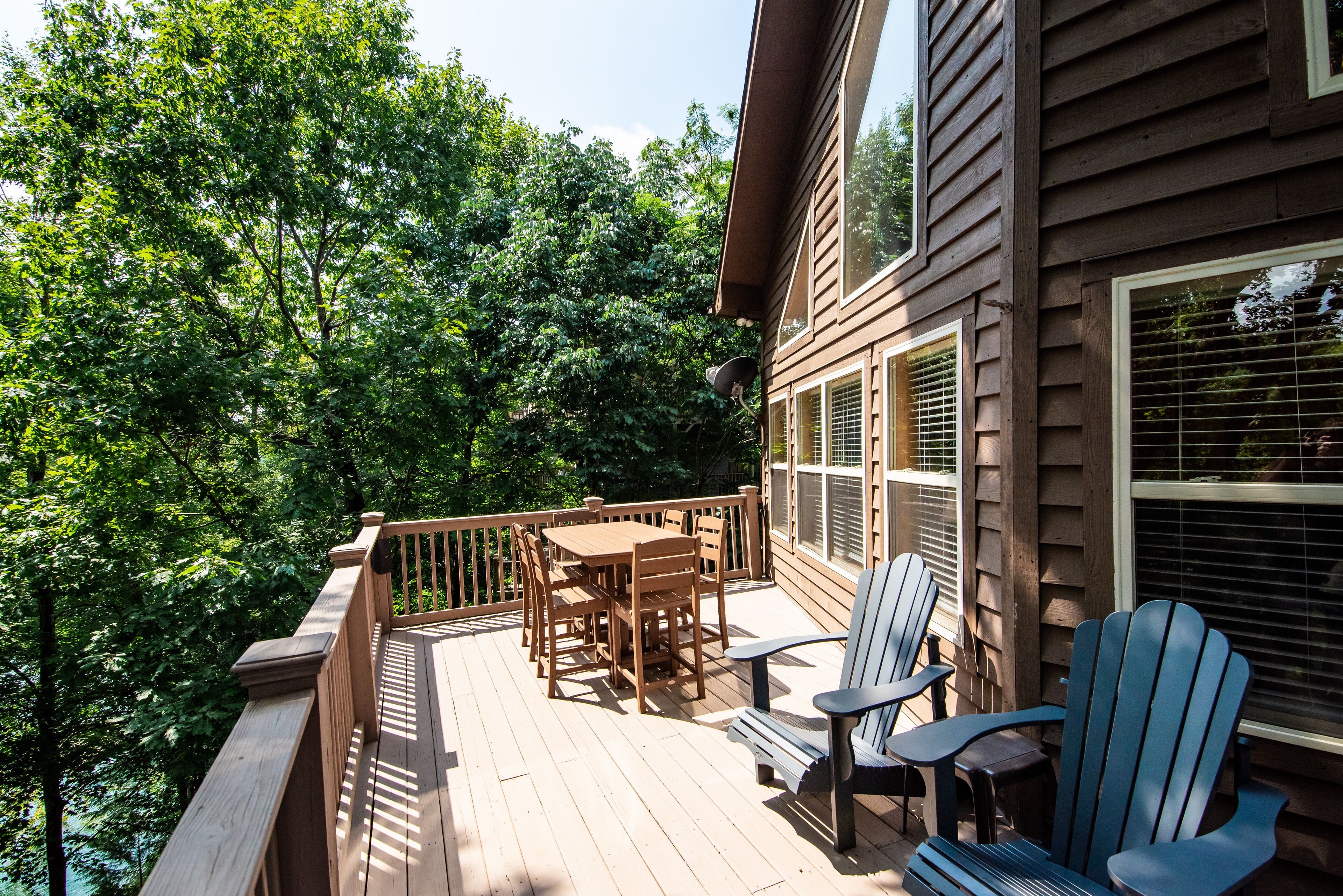 Une terrasse en bois avec une table et des chaises, entourée d’arbres.