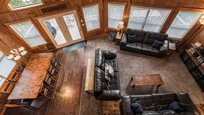 A spacious room with a large wooden dining table surrounded by chairs, a leather sofa set, and a coffee table.
