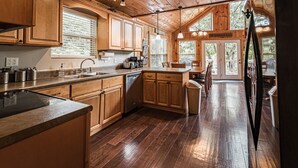 A spacious kitchen with wooden cabinets, a large island, and a dining area with a view of the outdoors.