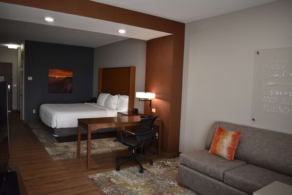 Una habitación de hotel con cama, escritorio, silla y sofá.