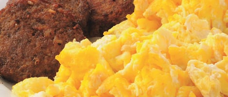 Scrambled eggs and two meat patties on a plate.