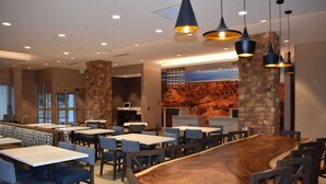 A restaurant with high tables and booths, stone accents, and pendant lighting. - La Quinta Inn & Suites by Wyndham Flagstaff East I-40 (Flagstaff)