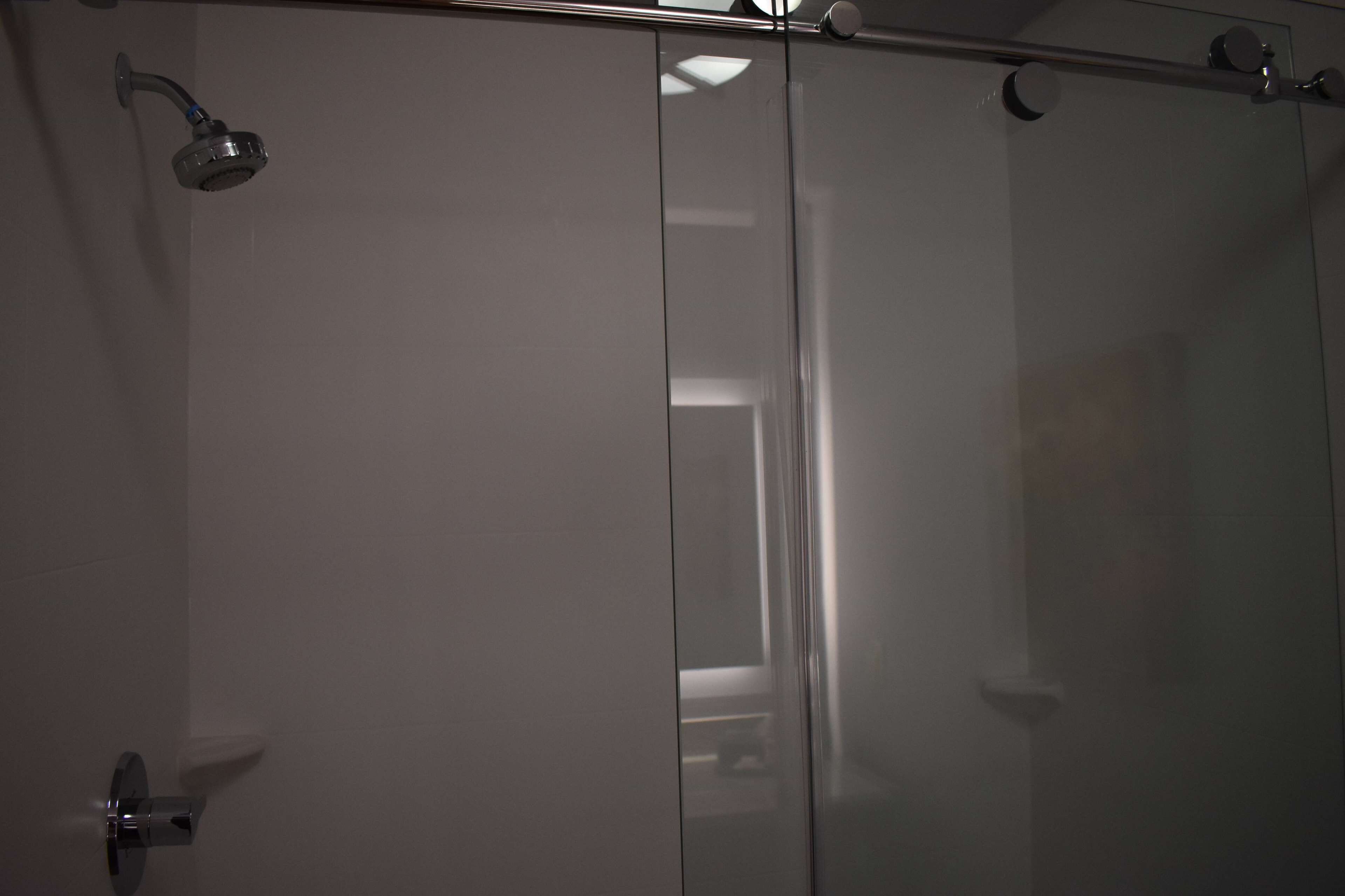 A modern bathroom with a glass shower enclosure, a visible toilet, and a showerhead.