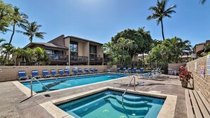 Une piscine avec des chaises longues et des palmiers.