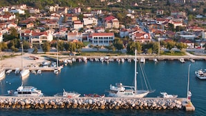 A marina with boats docked, surrounded by a residential area with houses and a hilly backdrop. - Alancia Suites (Kefalonia)