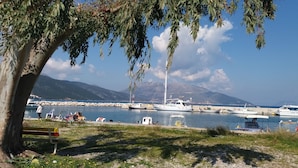 A marina with boats docked, a mountain in the background, and a tree in the foreground. - Alancia Suites (Kefalonia)
