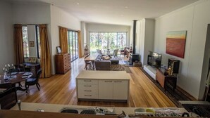 Uma sala de estar ampla com uma mesa de jantar, sofás e uma televisão.