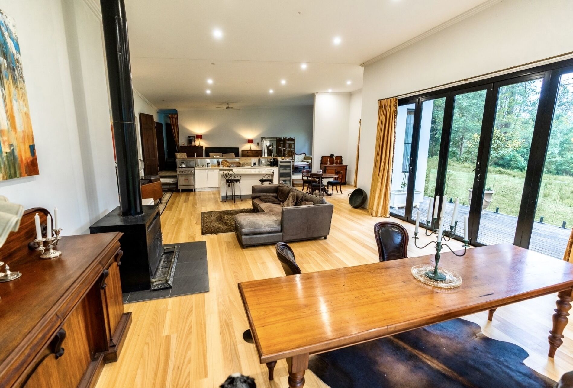 A spacious living area with a wooden dining table, a sofa, and a kitchen in the background.