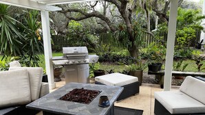 A covered outdoor patio with a grill, seating area, and potted plants. - Melbourne Beach getaway, Surfing, Birdwatching, nature. fishing. (Melbourne Beach)