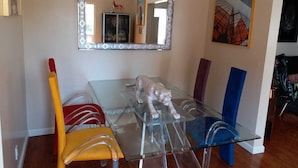 Un coin repas avec une table en verre, une sculpture d’animal décoratif et un miroir au-dessus.