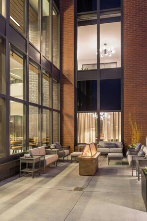 An outdoor seating area with a fire feature, large windows, and a brick wall. - SpringHill Suites by Marriott Madison (Madison)