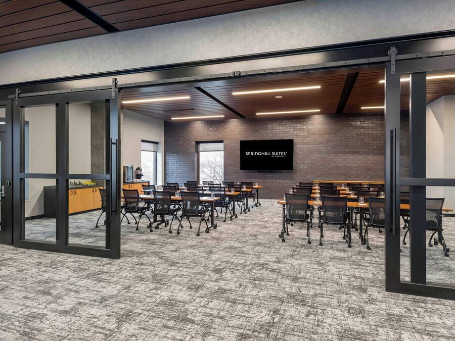 A conference room with a brick wall, a large screen, and multiple tables with chairs.