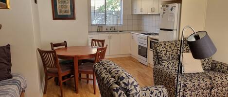 A compact living space with a dining area, kitchenette, and a patterned sofa.