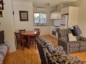 Um espaço compacto com área de refeições, cozinha compacta e sofá estampado.
