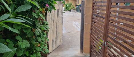A gated entrance with a concrete pathway leading to a building with a brick facade.