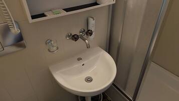 A bathroom with a white sink, a toilet, and a shower area.