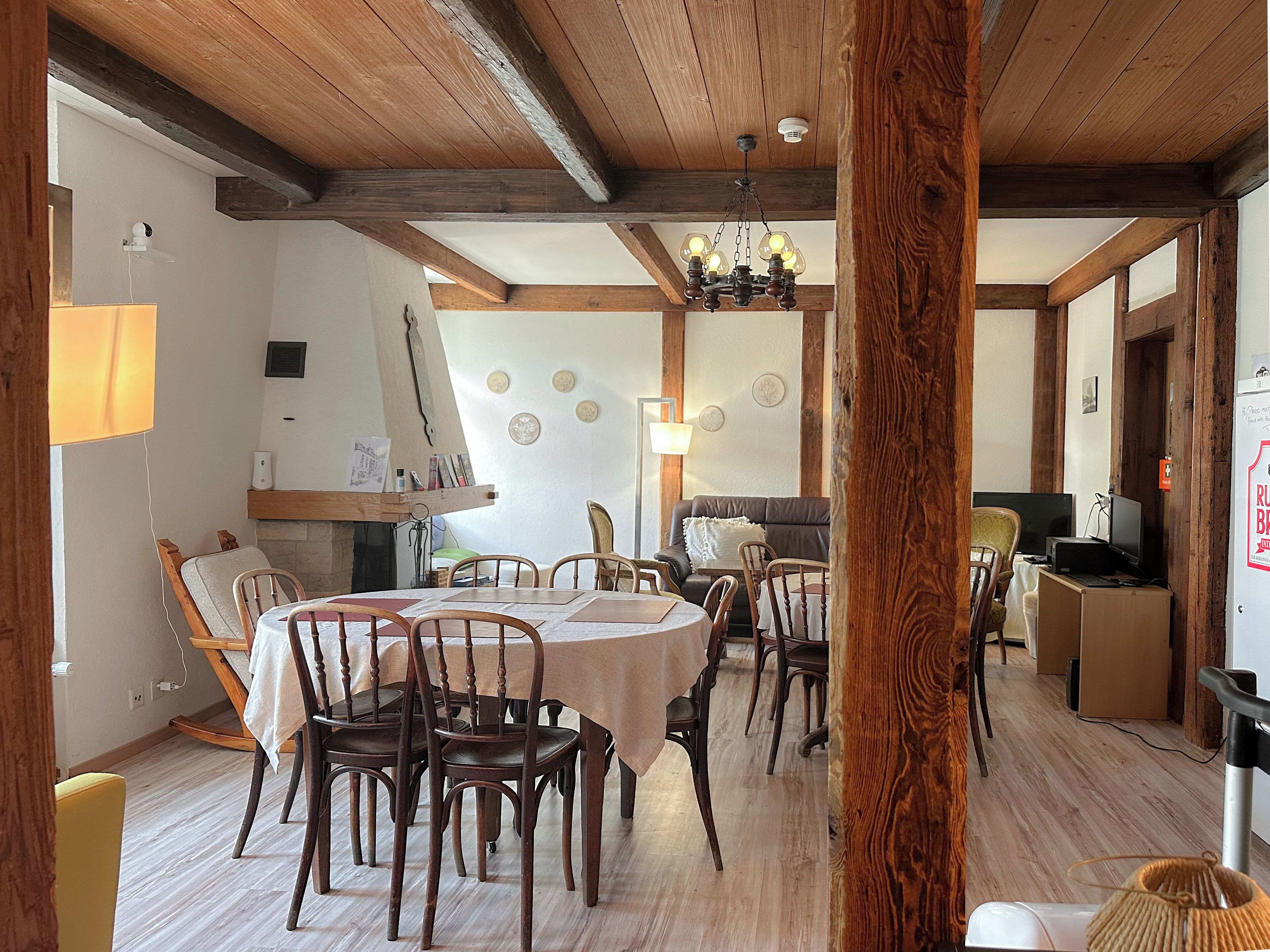 A dining area with wooden tables and chairs, a chandelier, and a fireplace.