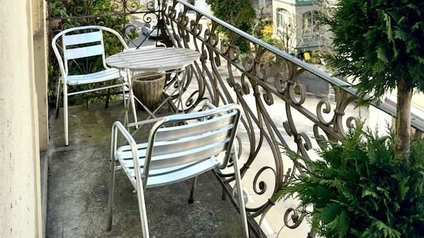 A balcony with metal chairs and a table, overlooking a town with traditional buildings and a mountain in the background. - Hotel Harder Minerva (Interlaken)