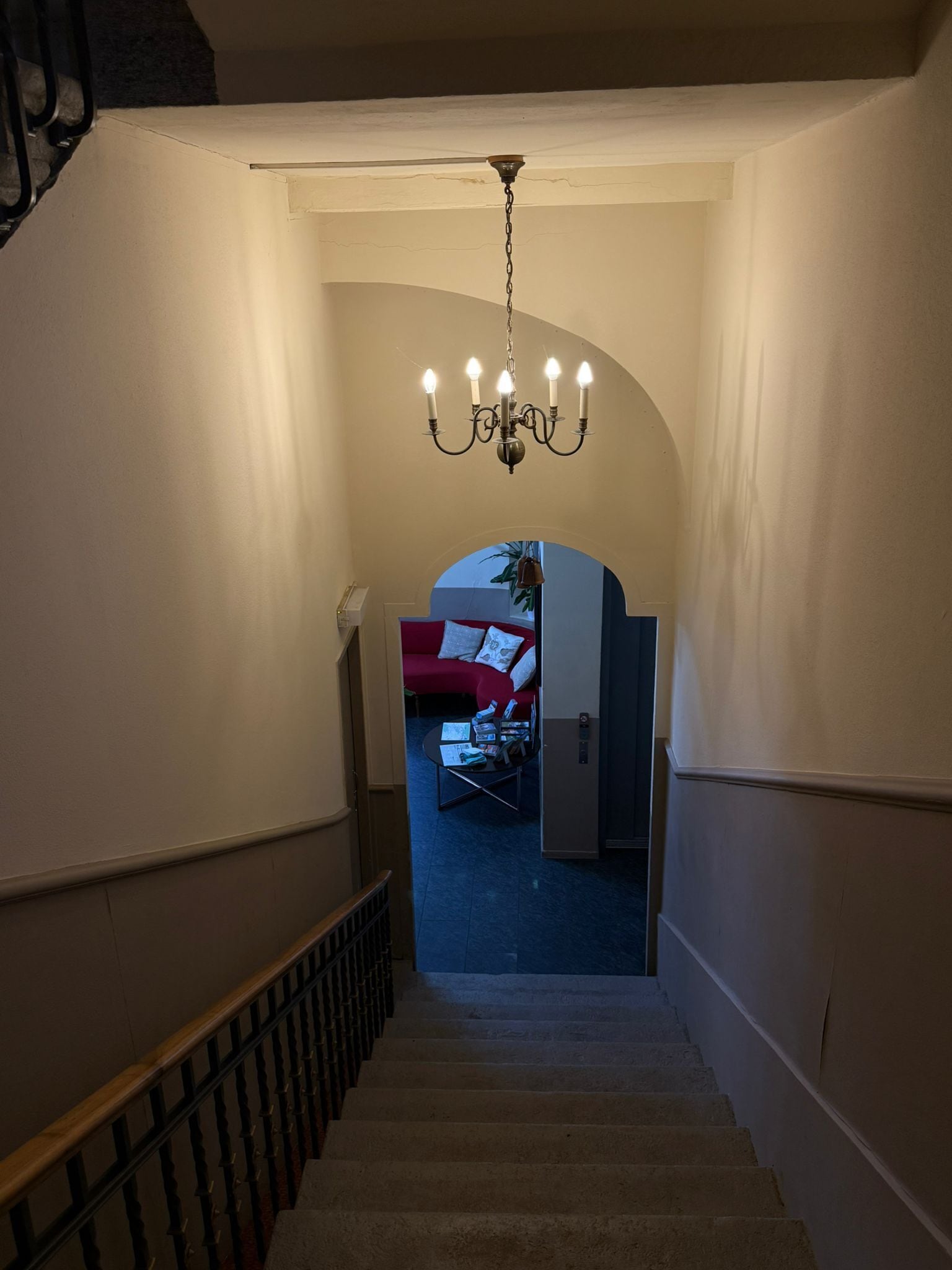 Een trap die leidt naar een kamer met een rode bank en een witte kast.