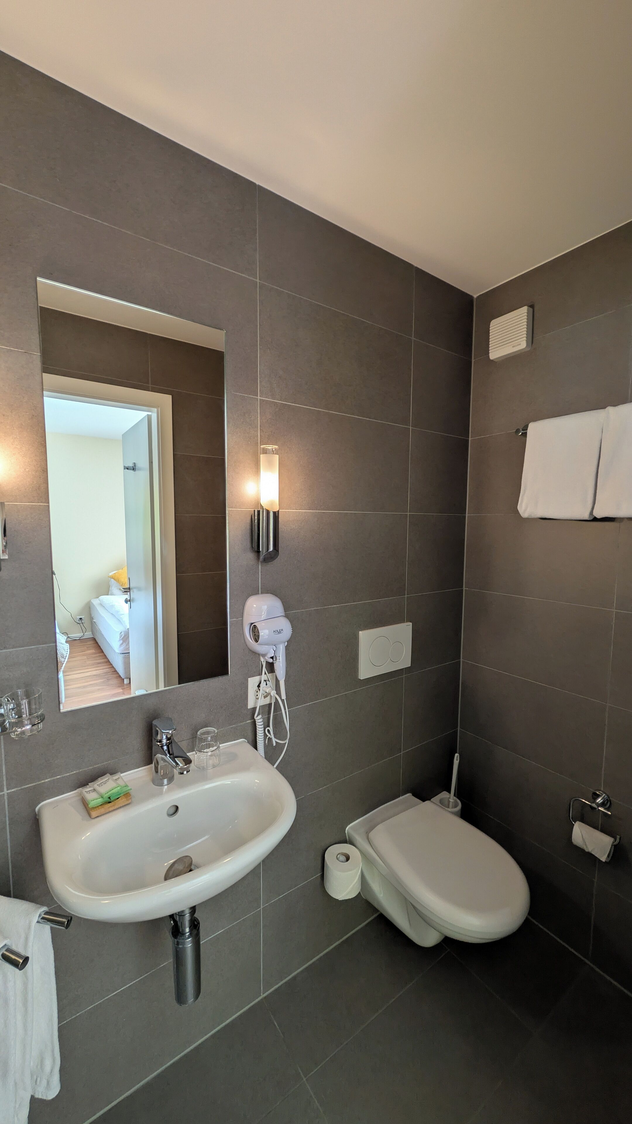Une salle de bain moderne avec un lavabo, des toilettes et un miroir.