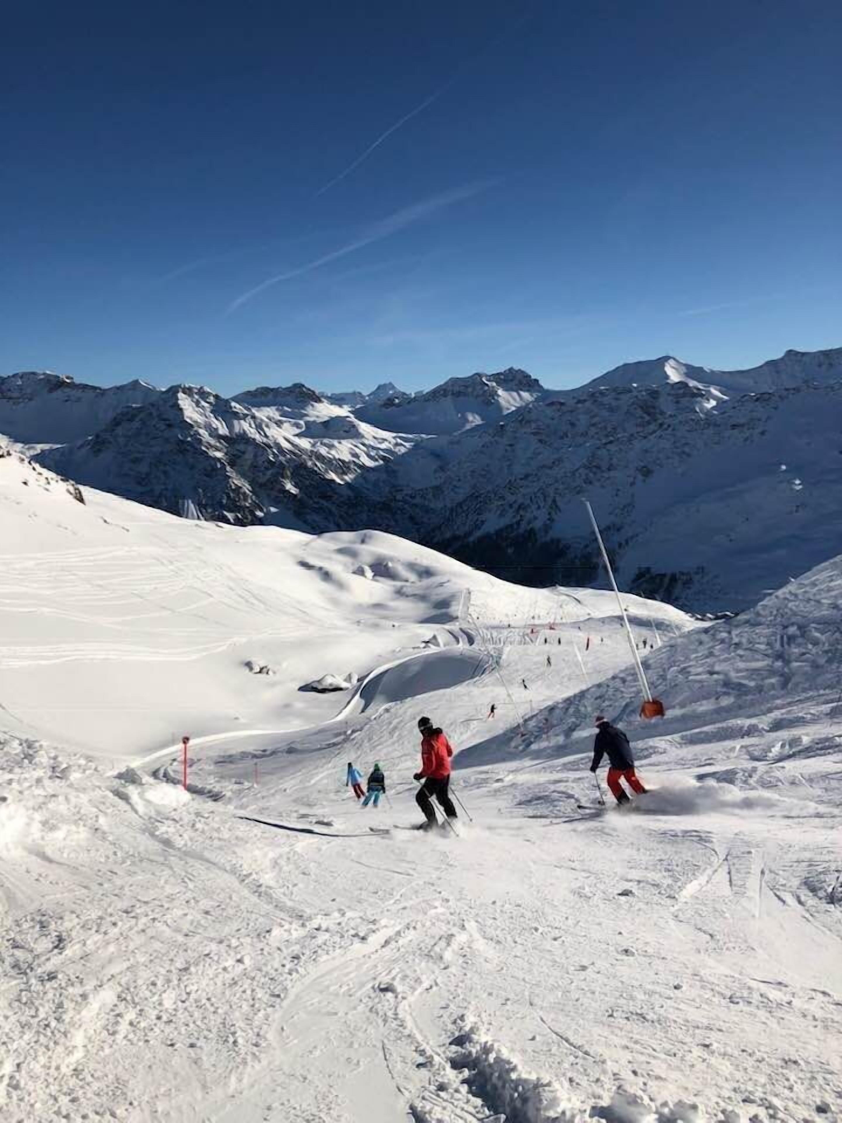 A snowy mountain slope with skiers and a ski lift.