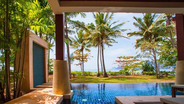 A pool area with a view of palm trees and a body of water. - Amatapura Beach 6 (Sai Thai)