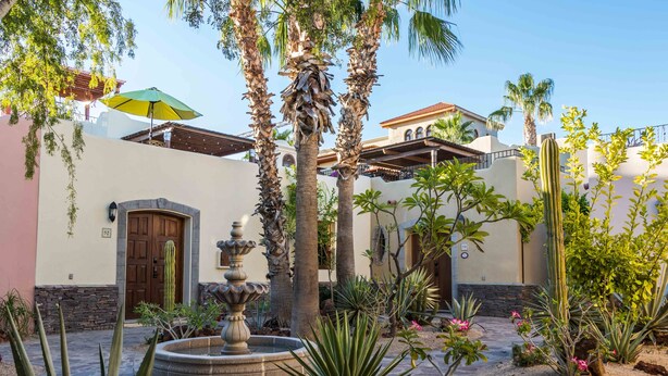 A courtyard with palm trees, a fountain, and a building with a door and window. - Casa Vista del Mar, Amazing Ocean View (Loreto)