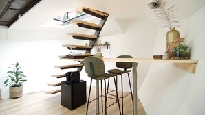 A modern kitchen with a unique staircase design, a wooden dining table, and a peacock feather decoration. - Bright & Spacious Studio @ eco houseboat! (Amsterdam-West)