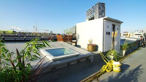 A rooftop terrace with a skylight, potted plants, and a small utility room. - Bright & Spacious Studio @ eco houseboat! (Amsterdam-West)
