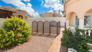 A residential area with a gated entrance, a pathway, and a building with a balcony. - CH Villa Cuenca Atalaya Park (Benijofar) (Ciudad Quesada)