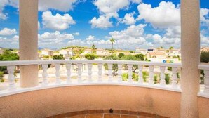 A balcony with a white balustrade, a tiled floor, and a view of a residential area with houses and greenery under a clear sky. - CH Villa Cuenca Atalaya Park (Benijofar) (Ciudad Quesada)