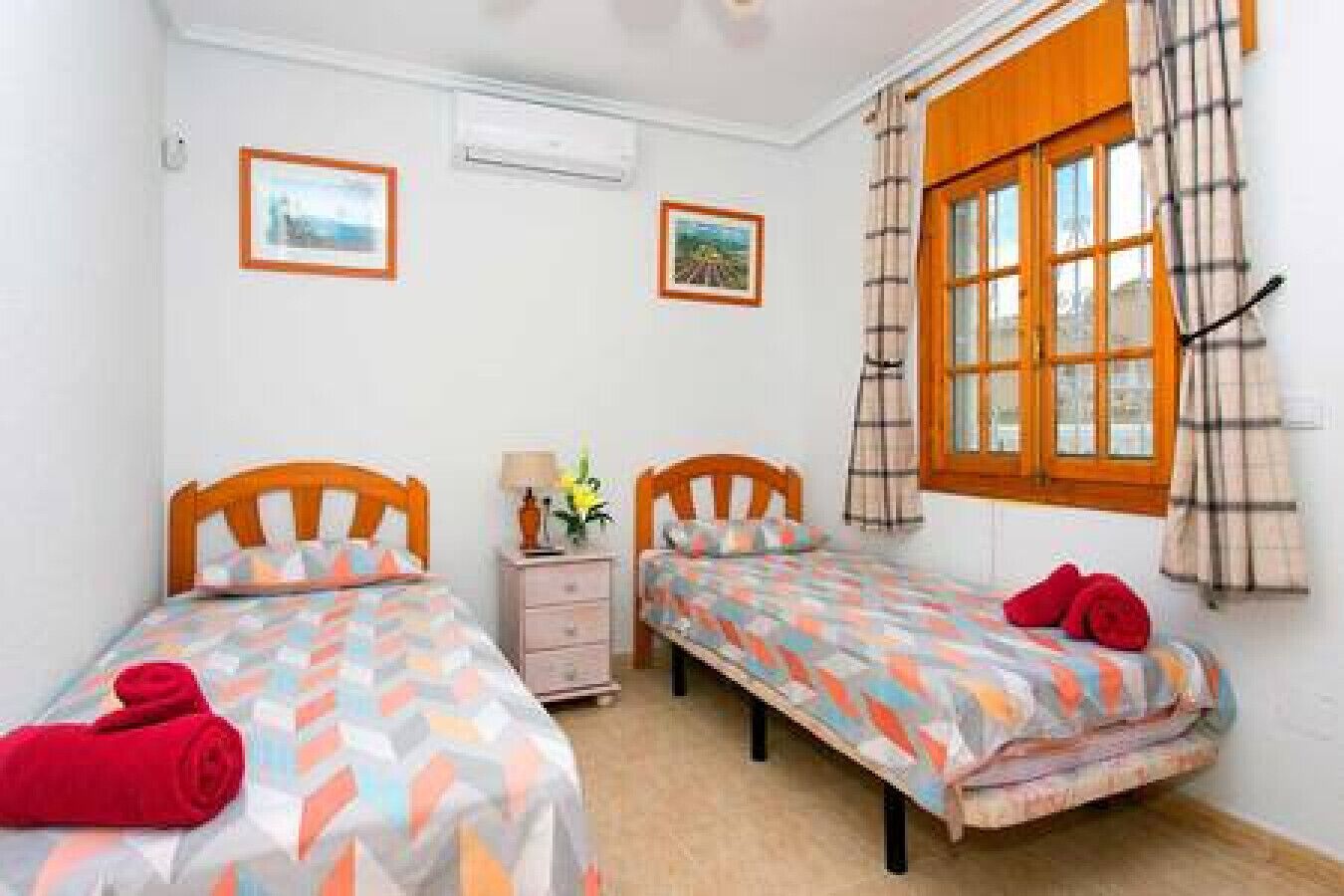 A bedroom with two single beds, a nightstand, and a window with curtains.