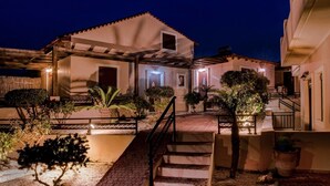 A two-story building with a tiled roof, a staircase leading to the entrance, and a well-lit outdoor area with potted plants. - Kyriaki' s Cozy Appartment (Chania)