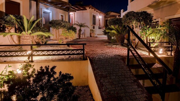 A courtyard with a paved pathway, potted plants, and a staircase leading to a second level. - Kyriaki' s Cozy Appartment (Chania)